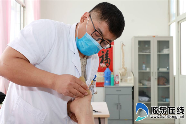 烟台山医院疼痛科门诊专家高建东正在为跟痛症患者做足部筋膜链手法松解