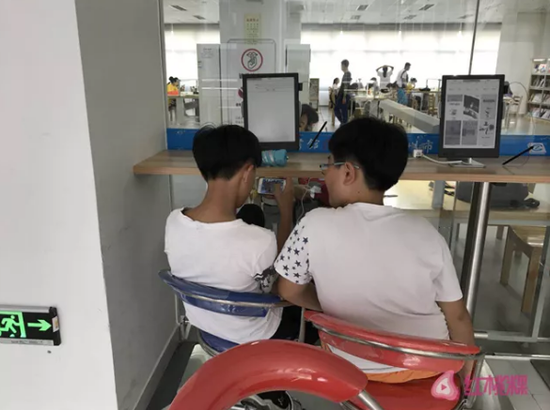 两位学生正在玩手机游戏